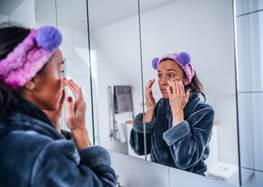 Kvinna i badrum och utför sin hudvårdsrutin