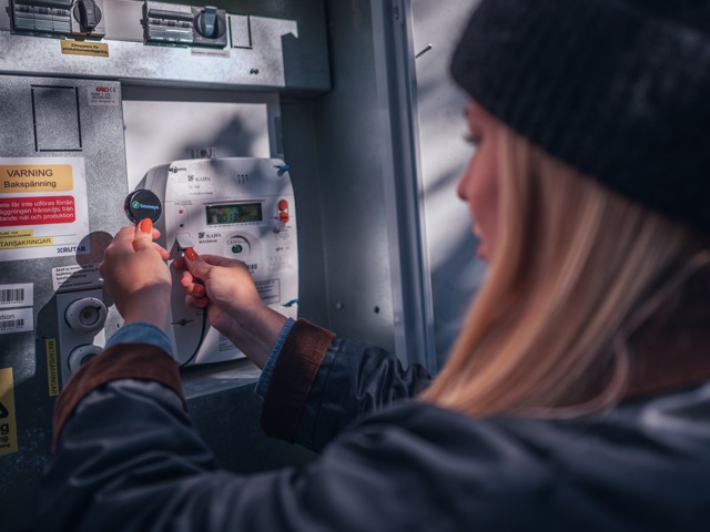 Kvinna ansluter realtidsmätare till elmätare