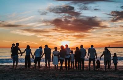 Barn och vuxna på en strand vid solnedgång