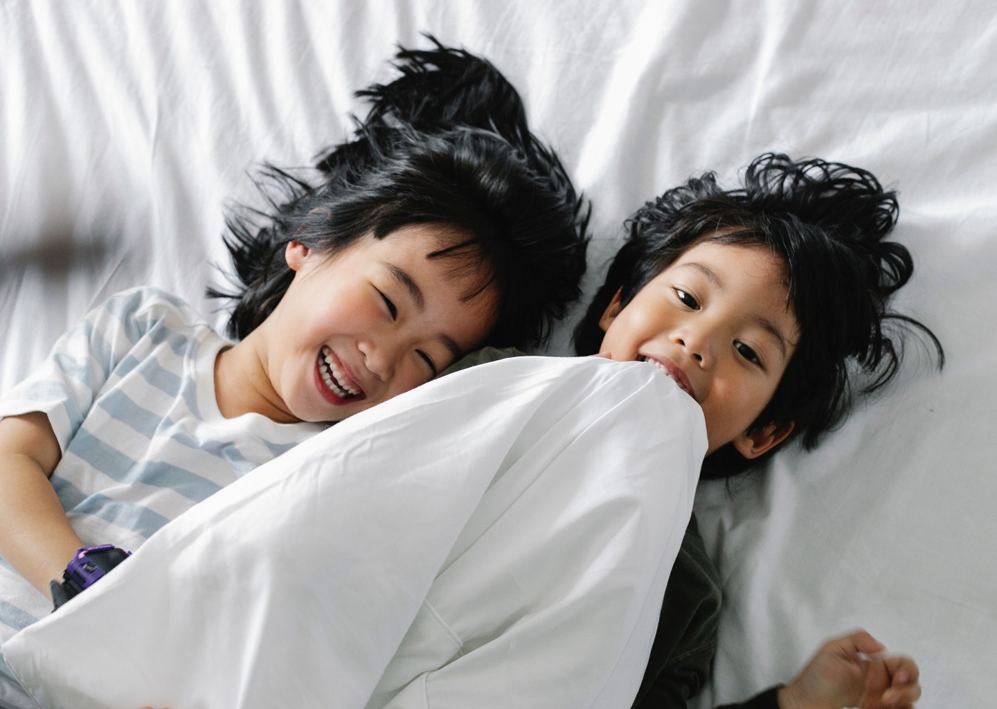 Skrattande barn i en säng