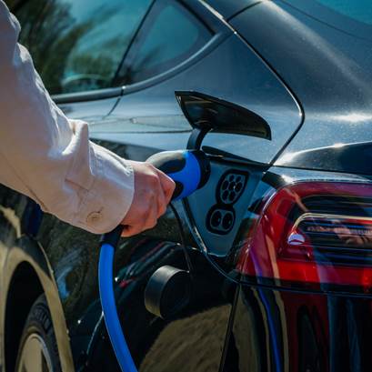 Person kopplar in laddare i elbil